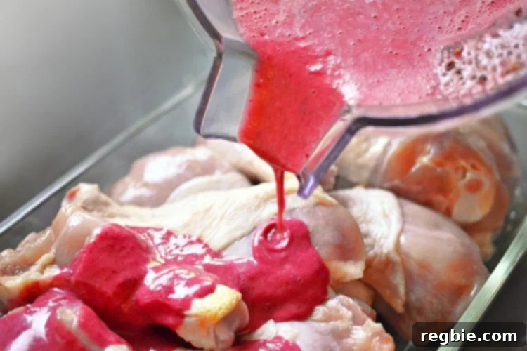 Wholesome Whole30 Cherry Chicken 8 Pouring the pink cherry marinade over the raw chicken drumsticks in a bowl.