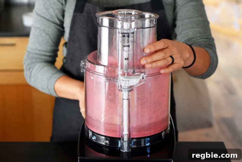 Peanut Butter Jelly Power Bites 3 Someone using a food processor to turn freeze dried raspberries into powder.