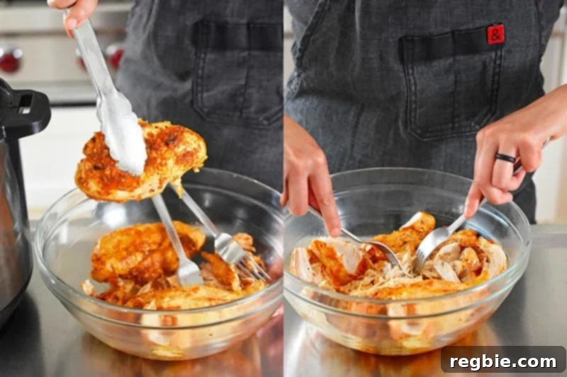 Instant Pot Whole30 Keto Salsa Chicken Tacos 7 Close-up of shredded Instant Pot Salsa Chicken in a bowl, being tossed with two forks, showcasing its tender texture ready for tacos.