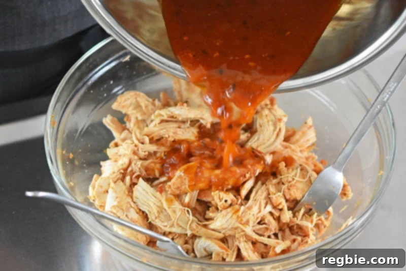 Instant Pot Whole30 Keto Salsa Chicken Tacos 8 A stream of rich, flavorful sauce being poured from the Instant Pot over a bowl of shredded Instant Pot Salsa Chicken, ready to be mixed for succulent tacos.