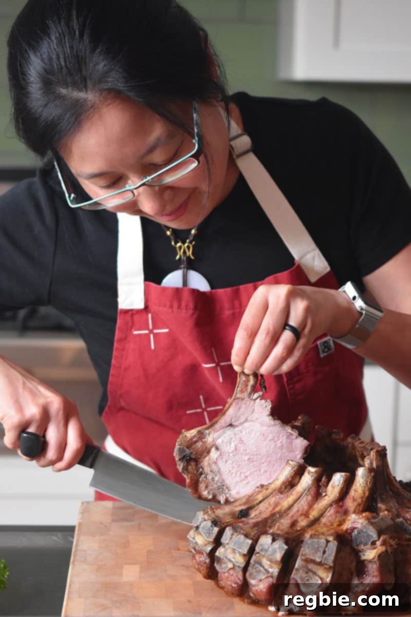 Someone slicing off a piece of the Magic Crown Roast of Pork, revealing its succulent interior.