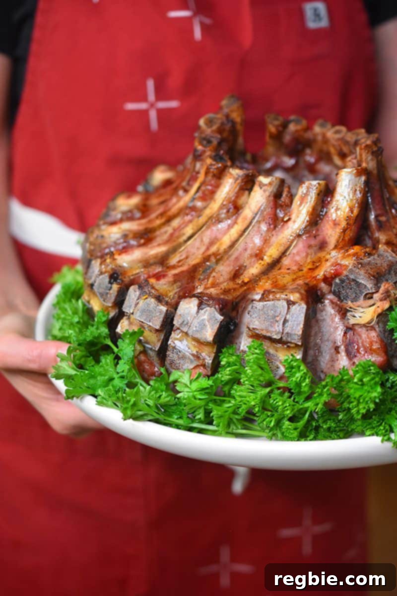 A close up of someone holding a plate of magic crown roast of pork, highlighting its perfectly cooked exterior.