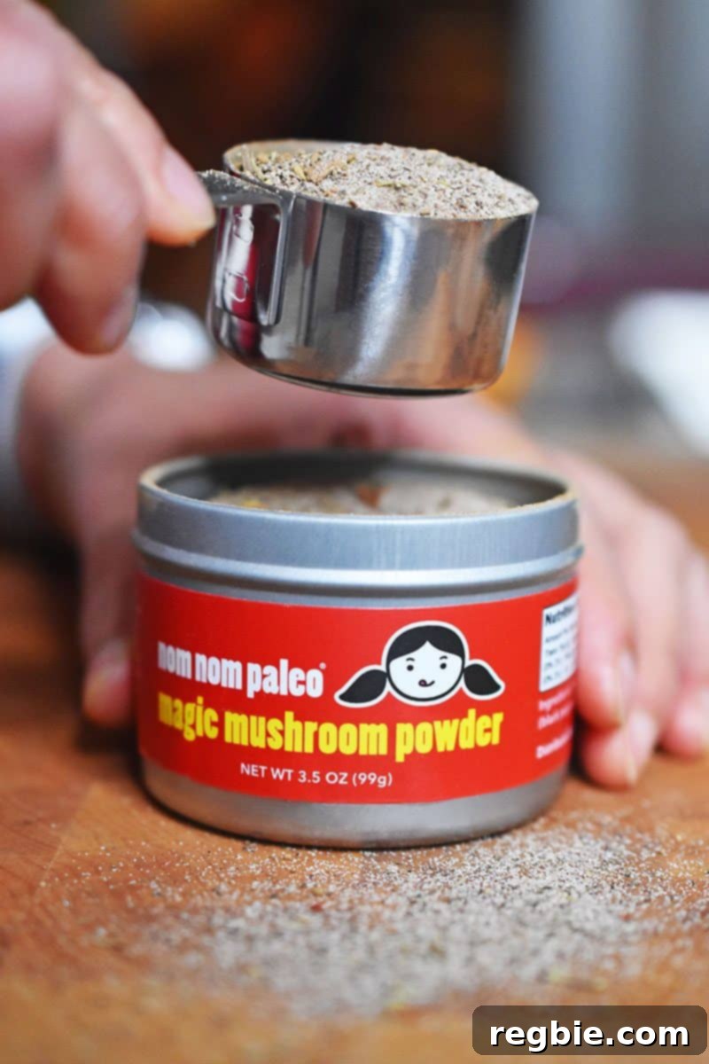 Scooping out Magic Mushroom Powder by Nom Nom Paleo, a flavorful seasoning for various dishes.