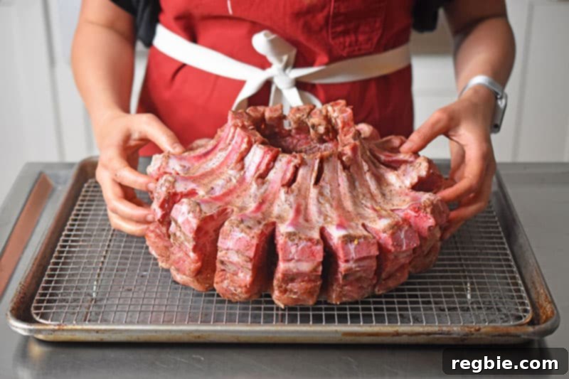 Someone placing the Magic Crown Roast of Pork on a wire rack on a sheet pan, ready for the oven.