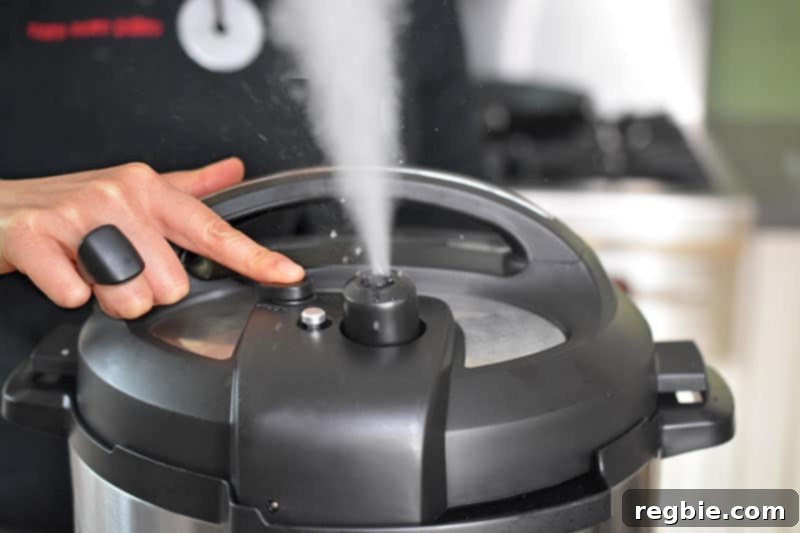 Instant Pot Wholesome Autumn Mash 12 A finger pressing the pressure release button on an Instant Pot, with steam visibly escaping, demonstrating a manual quick release.