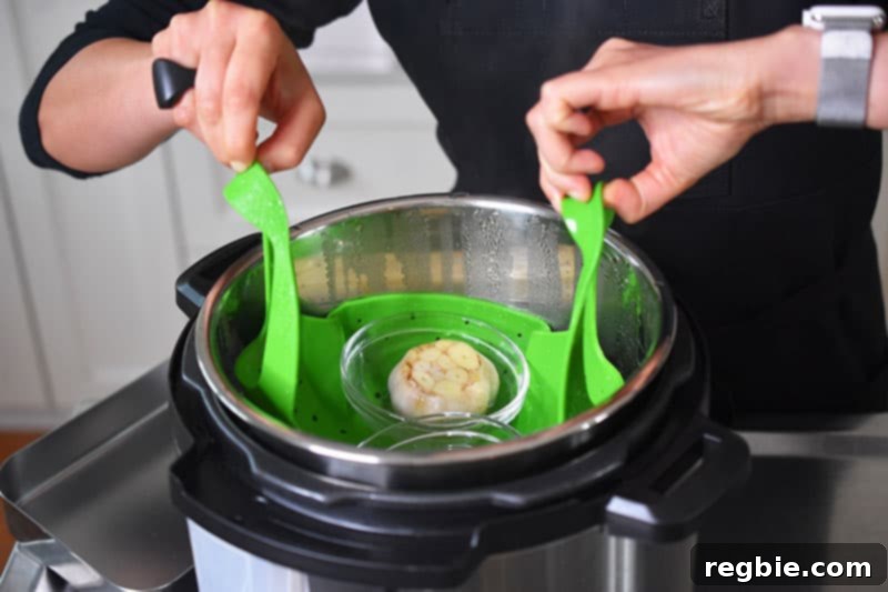 Instant Pot Wholesome Autumn Mash 4 Someone carefully lifting golden-brown roasted garlic bulbs out of an Instant Pot with tongs, showing the quick method.