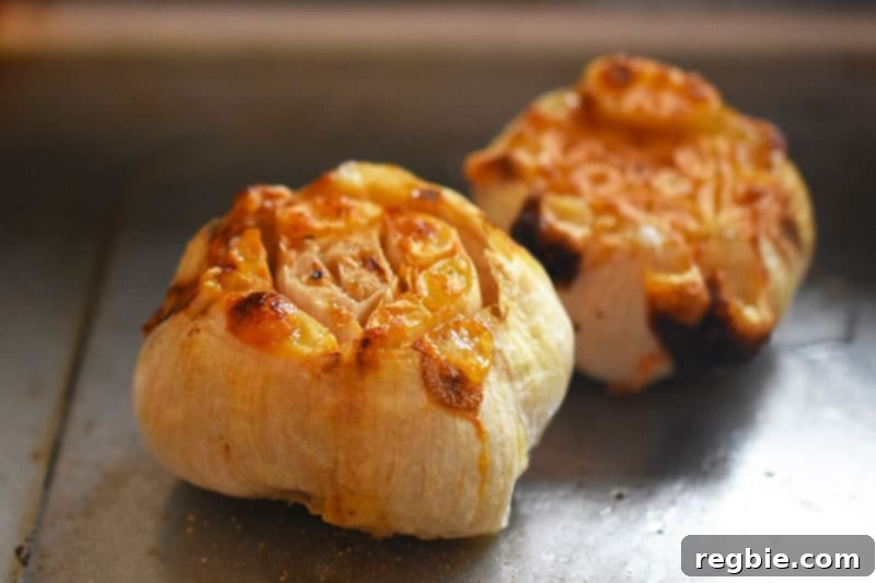 Instant Pot Wholesome Autumn Mash 5 Two beautifully roasted garlic bulbs, golden and soft, resting on a small sheet pan, ready to be used.