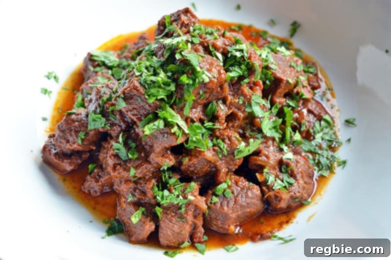Slow-Roasted Mexican Pulled Beef 8 An overhead shot of succulent Oven-Braised Mexican Beef on a white platter, garnished with fresh cilantro.