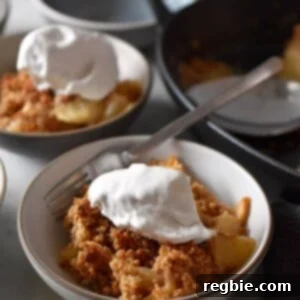 Two small, inviting dishes filled with paleo and gluten-free apple crisp, generously topped with a dollop of whipped coconut cream, offering a comforting and wholesome dessert.