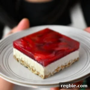 A delectable slice of grain-free, gluten-free, and dairy-free strawberry pretzel salad, perfectly composed on a white plate, showcasing its vibrant layers and inviting texture.
