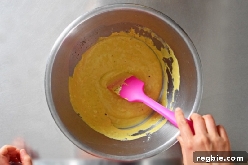 Someone mixing the marinade for the orange dijon chicken in a metal bowl.