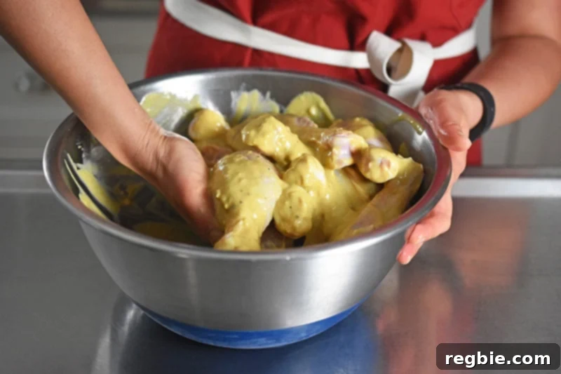 Someone mixing by hand the chicken drumsticks and orange marinade.