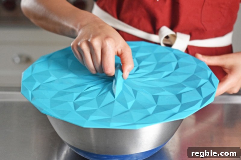 Someone covering a metal bowl with a silicone lid.
