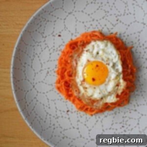 The completed dish: sweet potato hash topped with two fried eggs and a sprinkle of Aleppo pepper on a white plate.