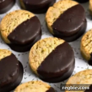 A closeup of a plate of chocolate dipped pistachio cookies, ready to be packaged as gourmet gifts.