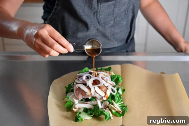 Someone pouring All-Purpose Stir-Fry Sauce on top of bok choy and chicken for the paper-wrapped chicken recipe.