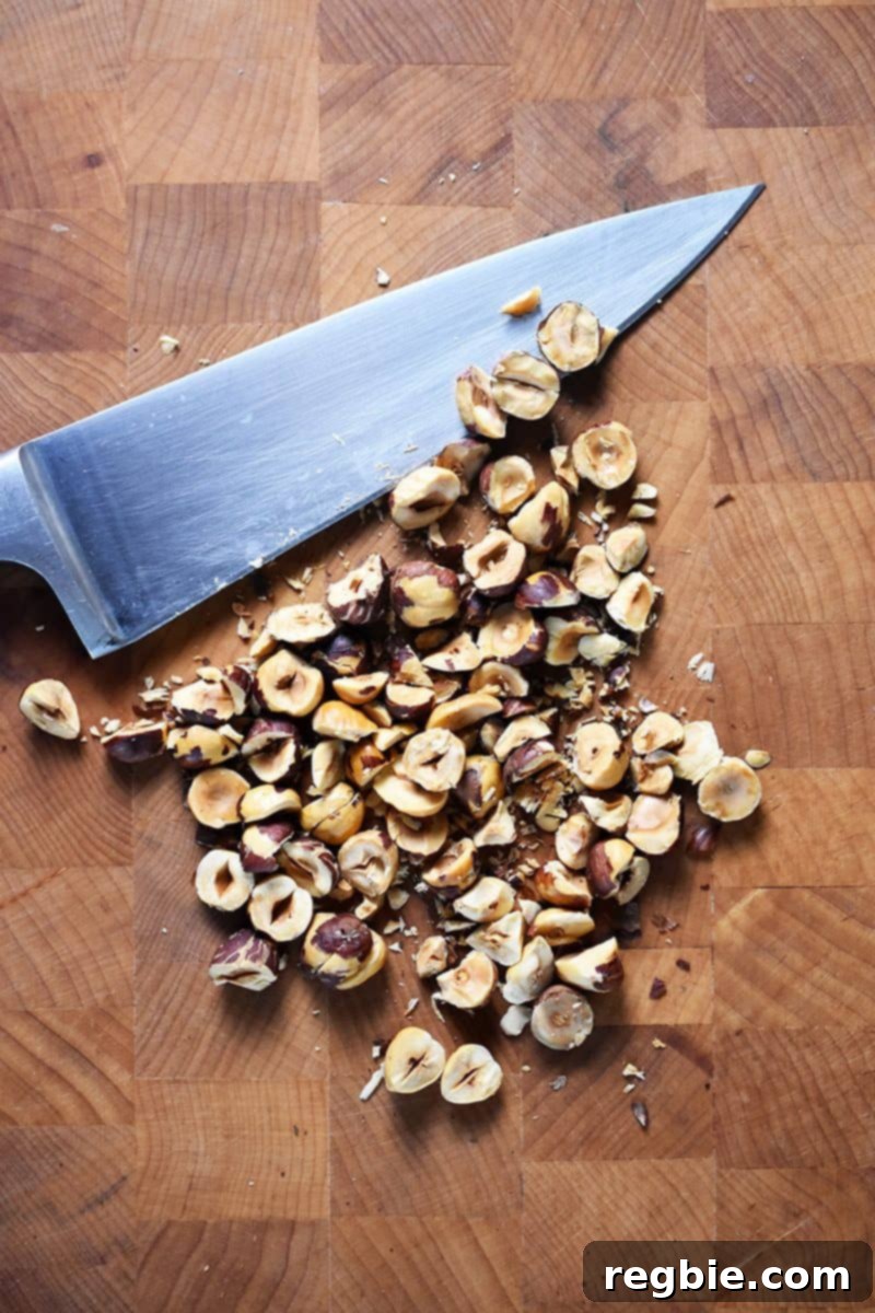 Golden Apple & Bitter Greens 8 Chopped hazelnuts on a cutting board with a chef's knife.