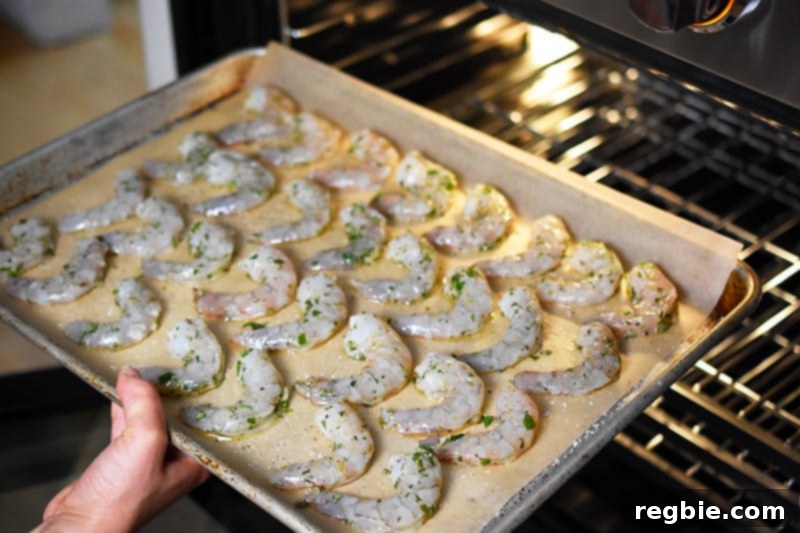Someone carefully placing the baking sheet with paleo shrimp into the preheated oven.