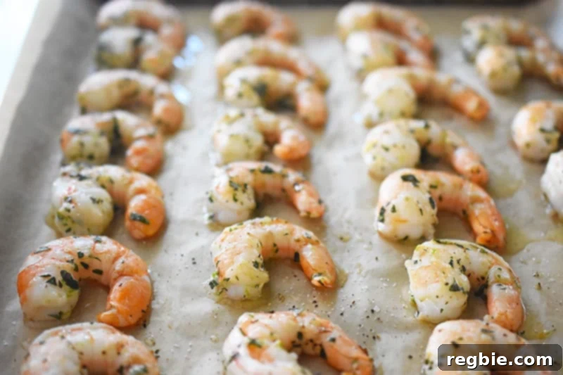 Perfectly roasted paleo shrimp on a parchment-lined baking sheet, lightly cooked and slightly pink, indicating ideal doneness.