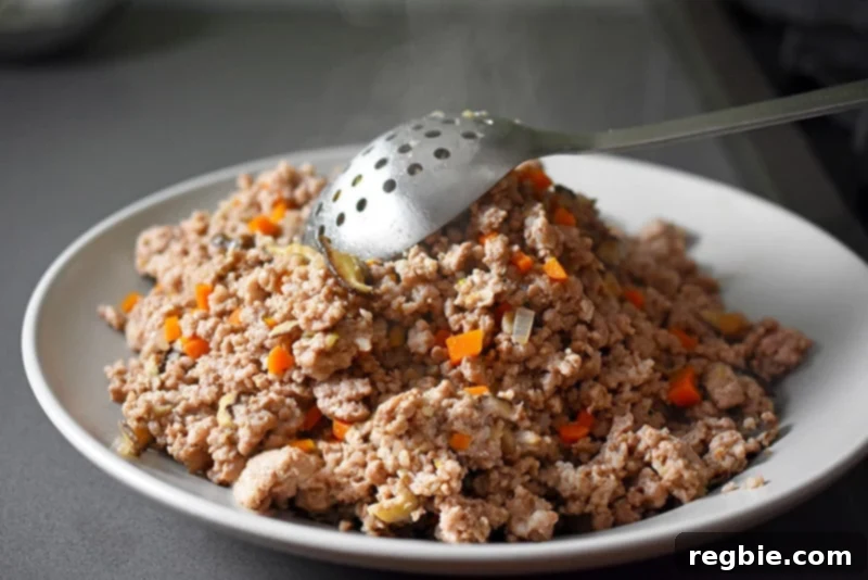 Using a slotted spoon to transfer the cooked pork and vegetables from the skillet to a plate, leaving the flavorful cooking liquid behind.