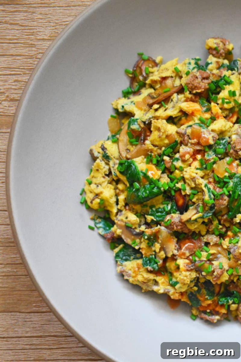 An overhead shot of Joe’s Special Scramble on a gray plate, garnished with fresh chives, highlighting its rich textures and vibrant ingredients.