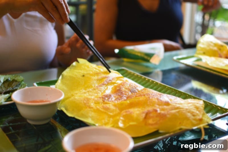 Enjoying crispy Bánh Xèo, a savory Vietnamese crepe, during the VietNomNomPaleo trip.