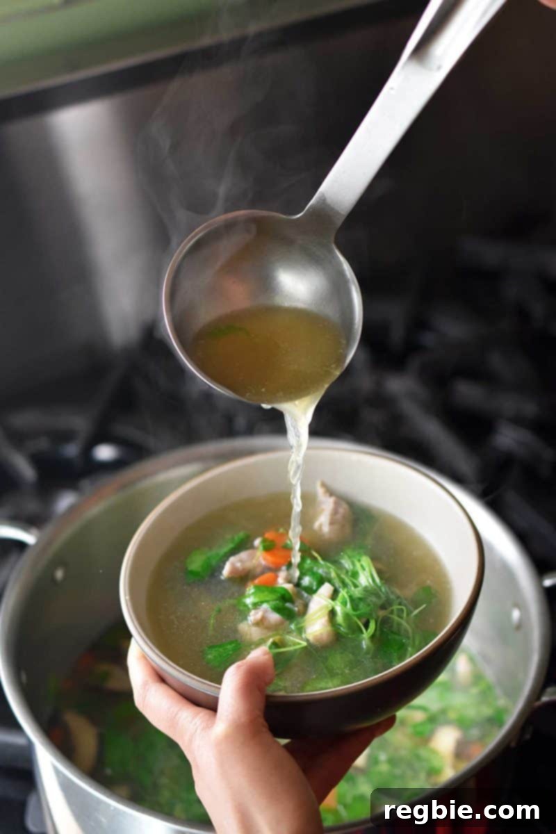 Expertly ladling steaming Watercress & Chicken Soup into a beautiful white bowl, ready to serve.