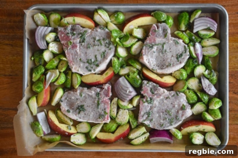 An overhead shot of Sheet Pan Pork Chop Supper ready for the oven, with all ingredients neatly arranged.