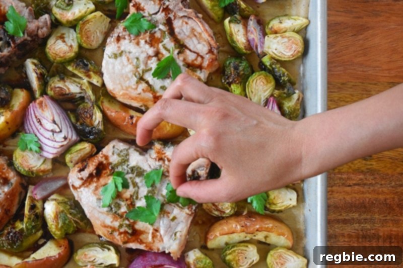 Adding fresh Italian parsley to Sheet Pan Pork Chop Supper after broiling, ready to be served.
