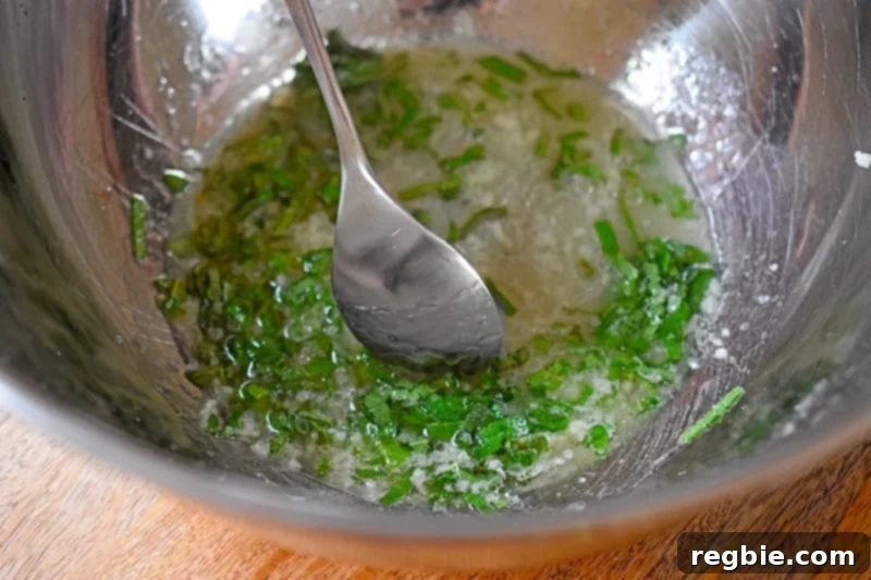 Stirring the marinade for Sheet Pan Pork Chop Supper with a spoon, showing a well-mixed blend of oil, lemon, sage, garlic, and salt.