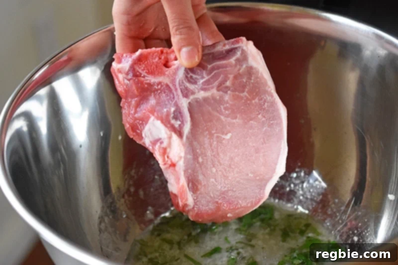 Adding the pork chops to the marinade, showing several bone-in pork chops being dropped into the bowl.