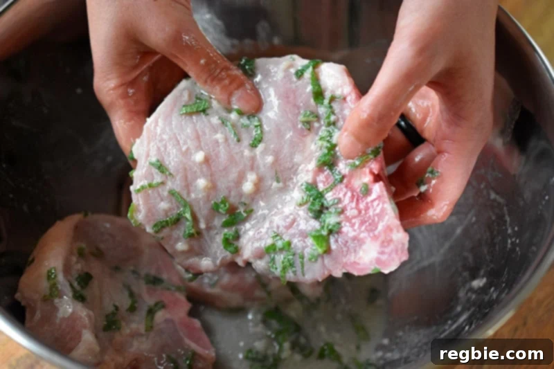A pork chop covered in marinade, showcasing a single chop thoroughly coated in the herb and citrus mixture.
