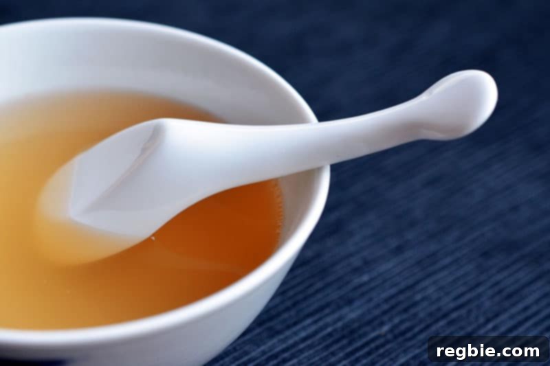 Nourishing Instant Pot Bone Broth 3 A bowl of rich chicken bone broth with a spoon, highlighting its gelatinous texture.