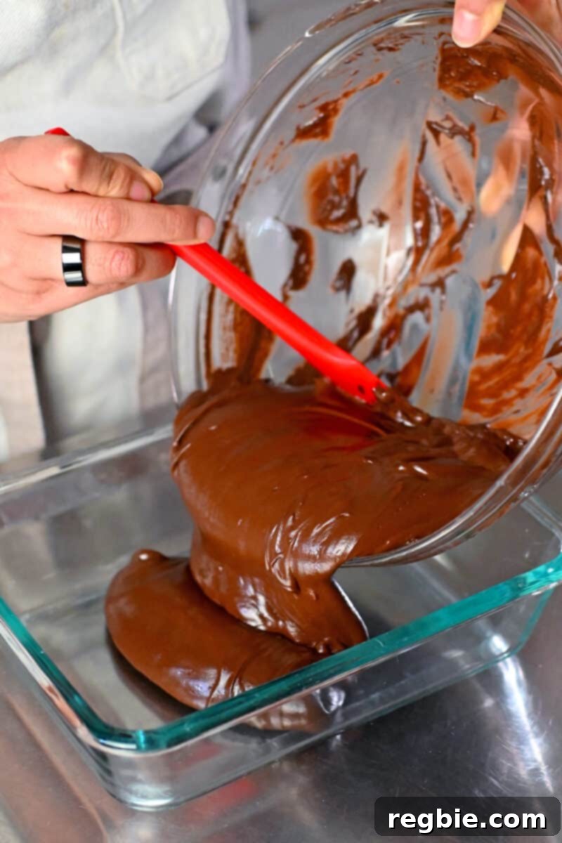 Pouring the paleo and vegan ganache into a glass storage container before chilling, showing preparation for the setting phase.