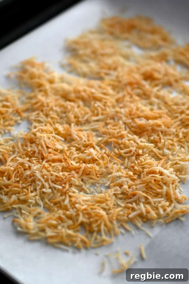 A closeup of the toasted shredded coconut on a rimmed baking sheet, showcasing the perfect golden-brown color for truffle coating.