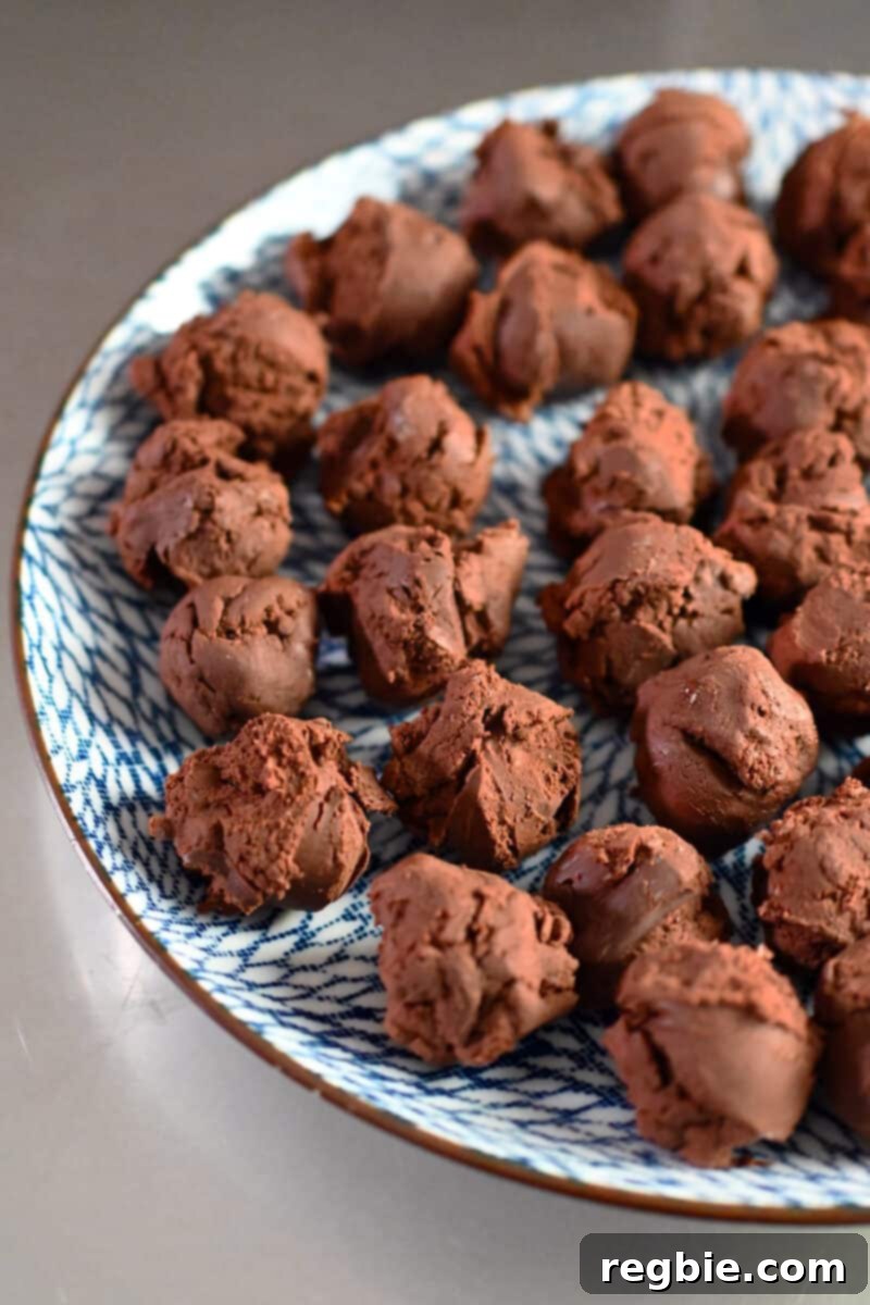 A blue and white plate filled with pre-portioned ganache balls that are about 1-inch in diameter, ready for rolling into truffles.