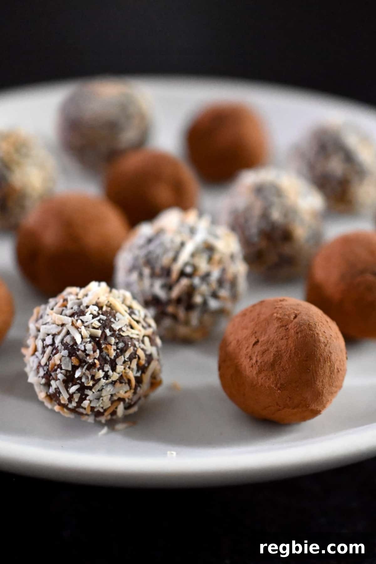 A closeup of Nom Nom Paleo Chocolate Truffles arranged in a neat row, coated with either cocoa powder or toasted coconut.