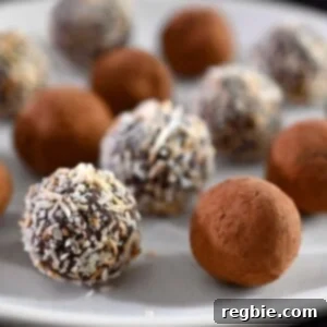 A closeup of a plate filled with Nom Nom Paleo vegan chocolate truffles topped with cocoa powder or toasted shredded coconut.