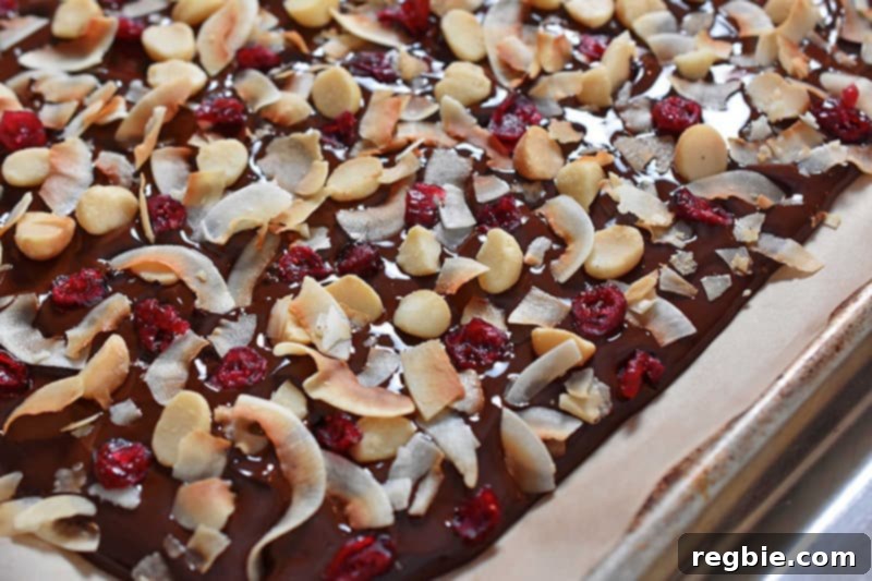 Coco-Nutty Dark Bark by Michelle Tam / Nom Nom Paleo https://nomnompaleo.com showing toppings being gently pressed into the chocolate.