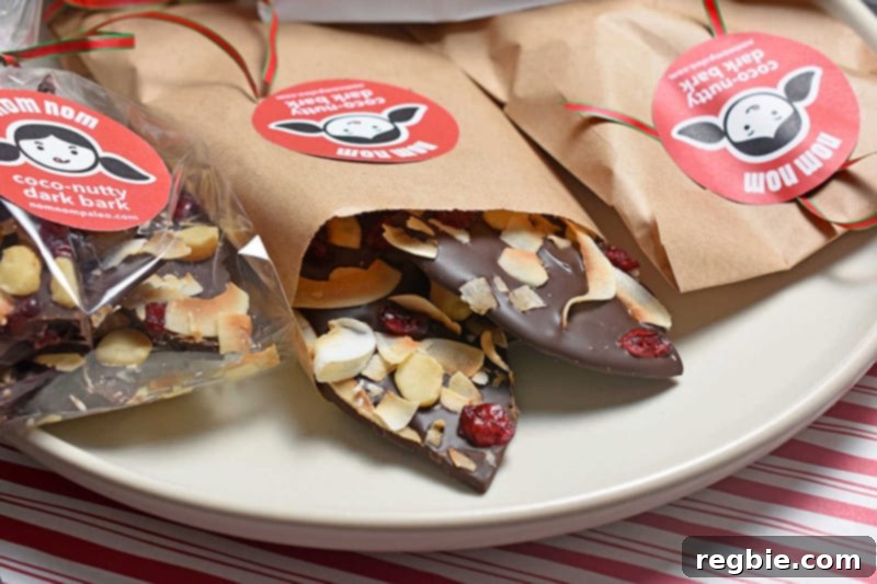 Coco-Nutty Dark Bark by Michelle Tam / Nom Nom Paleo https://nomnompaleo.com with various toppings including toasted coconut, dried cranberries, and macadamia nuts.