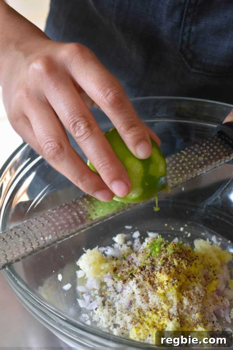 The Camp That Made Us Smarter and Stronger 8 A microplane grater in action, finely grating a piece of ginger, with other fresh ingredients like lemongrass and turmeric nearby.
