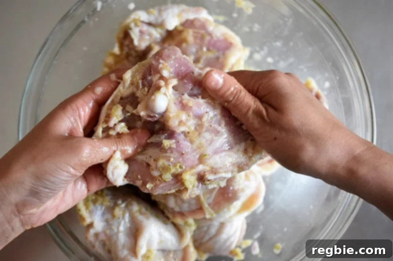 Massaging chicken thighs with the aromatic Vietnamese Lemongrass Chicken marinade to ensure deep flavor penetration.