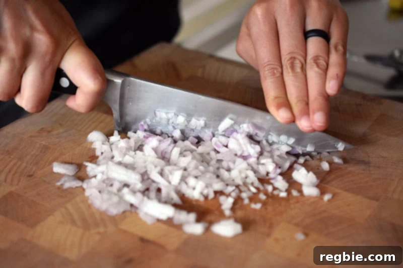 Mincing shallots on a wooden cutting board, a crucial step for the Vietnamese Lemongrass Chicken marinade.