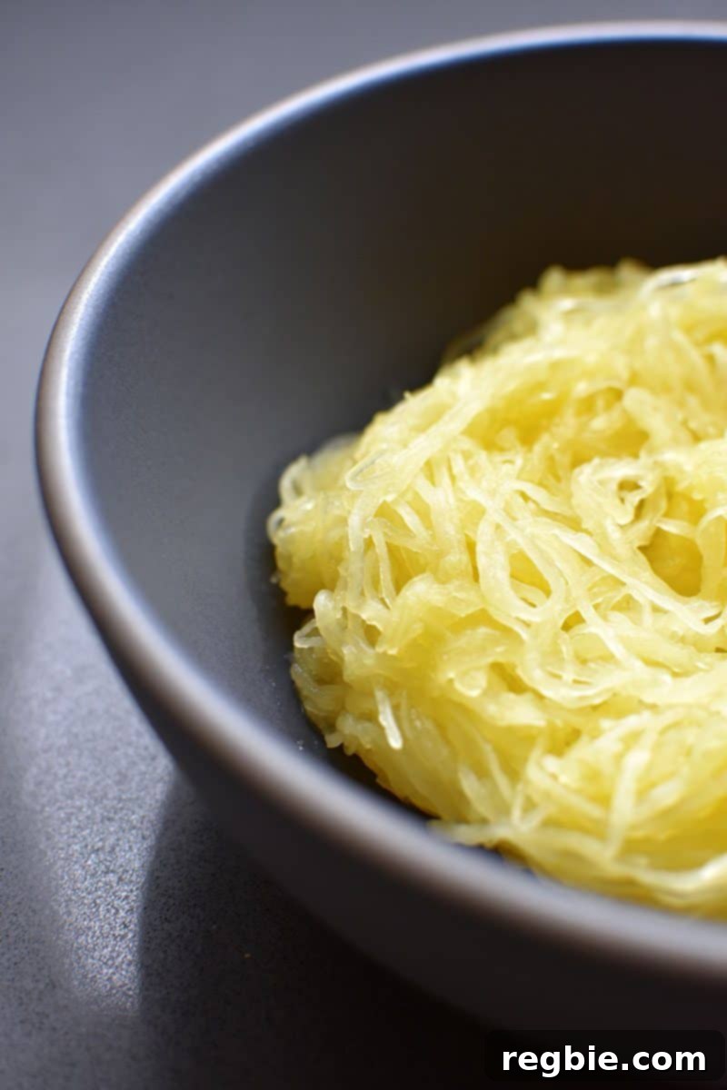 Quick Foolproof Instant Pot Spaghetti Squash 3 A close-up shot of perfectly cooked spaghetti squash in a beautiful blue-gray bowl, showcasing its delicate, noodle-like strands, ready to be tossed with sauce.