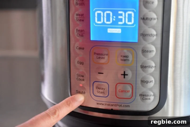 Someone pressing the Saute button on the front panel of an Instant Pot.