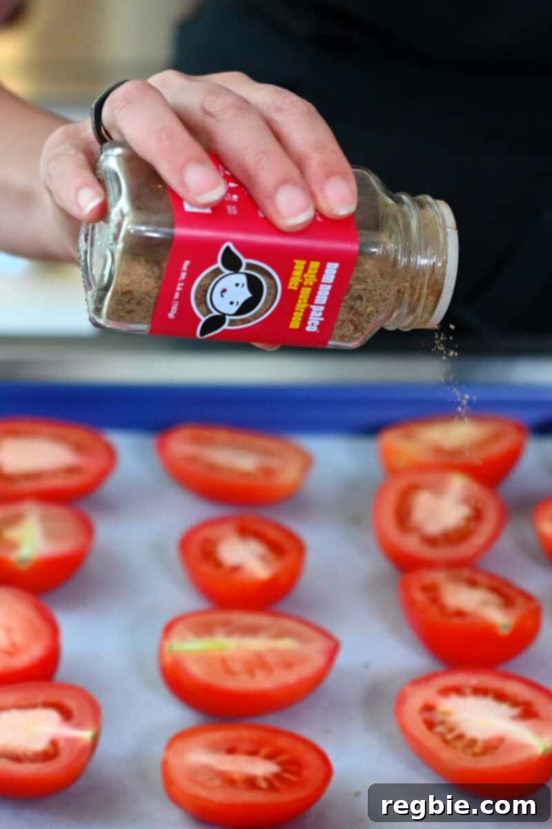Umami-Packed Oven-Roasted Tomatoes: Easy, Whole30, Keto, Low Carb 7 Sprinkling a jar of Magic Mushroom Powder onto halved plum tomatoes on a baking sheet.