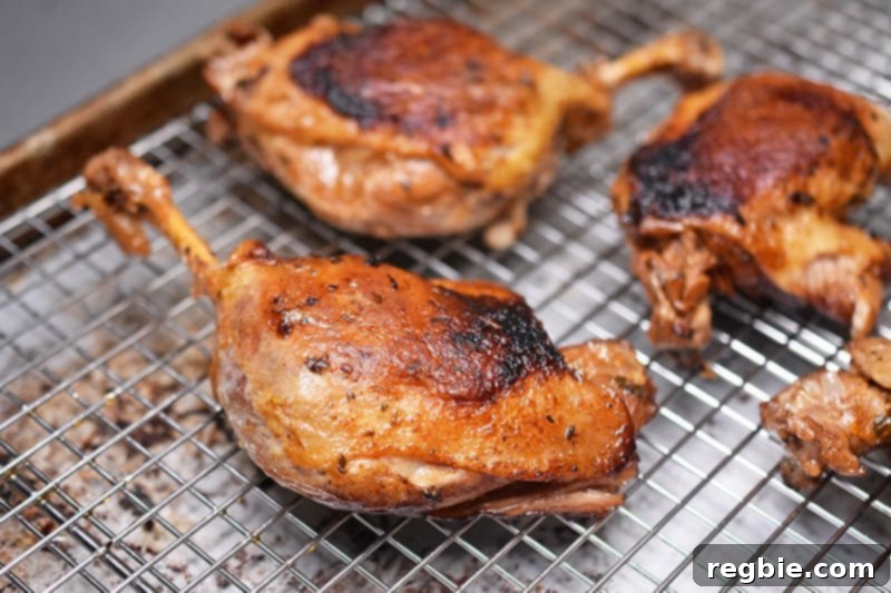 Instant Pot (Pressure Cooker) Orange Duck legs arranged on a wire rack lined baking sheet, ready for broiling to crisp the skin.