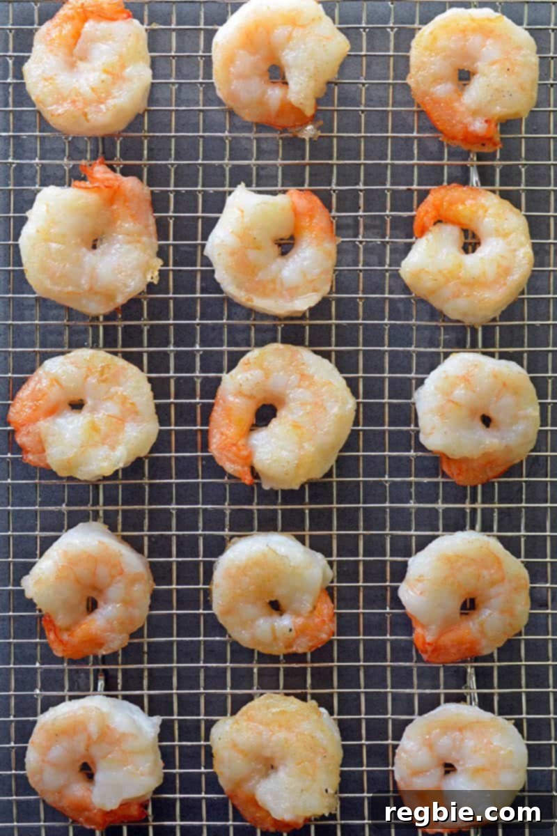 Crispy Paleo Walnut Shrimp resting on a wire rack, draining excess oil before being tossed in the sauce.