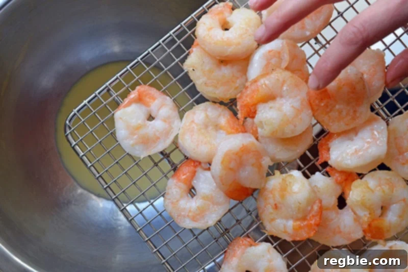 Adding the freshly fried shrimp to the creamy honey-mayo dressing for Paleo Walnut Shrimp.