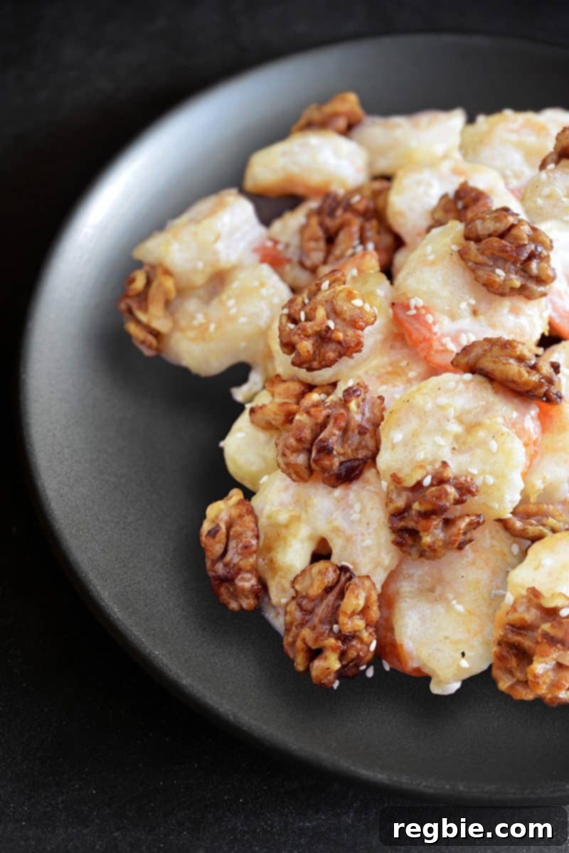 A beautifully presented black plate topped with a generous serving of Paleo Walnut Shrimp, ready to be enjoyed.